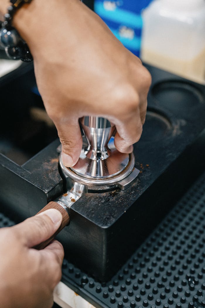 Close-up of a barista tamping espresso grounds, illustrating precision coffee-making techniques.